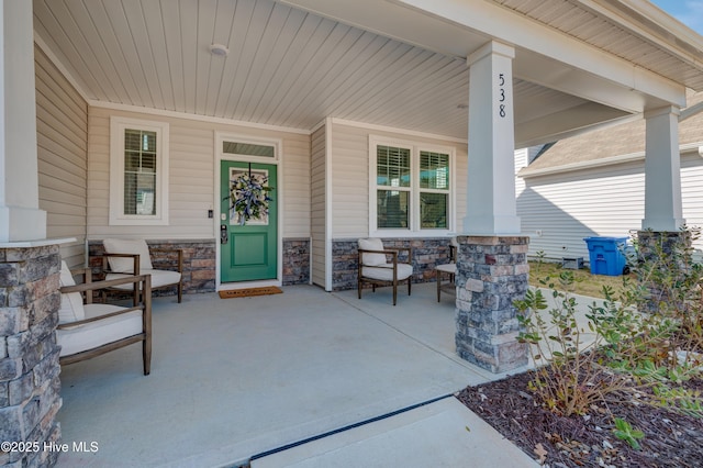 view of exterior entry featuring covered porch and stone siding