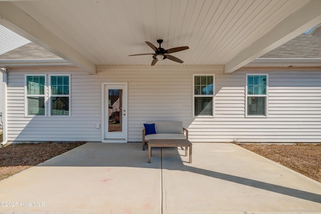 entrance to property featuring a shingled roof, ceiling fan, and a patio