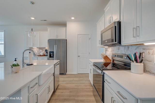 kitchen featuring stainless steel appliances, visible vents, light wood finished floors, and white cabinetry