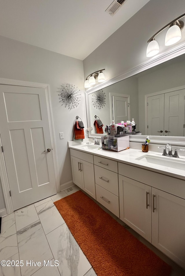 bathroom with marble finish floor, double vanity, a sink, and visible vents