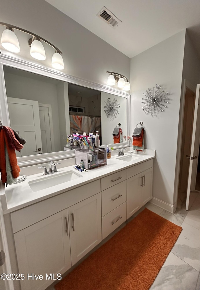 bathroom featuring marble finish floor, visible vents, a sink, and double vanity