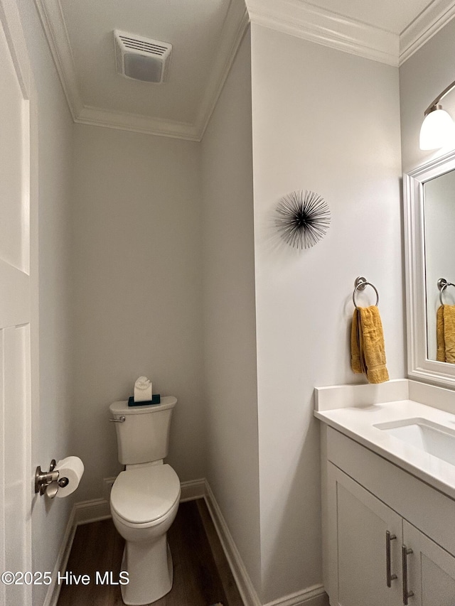 bathroom with toilet, wood finished floors, vanity, visible vents, and ornamental molding