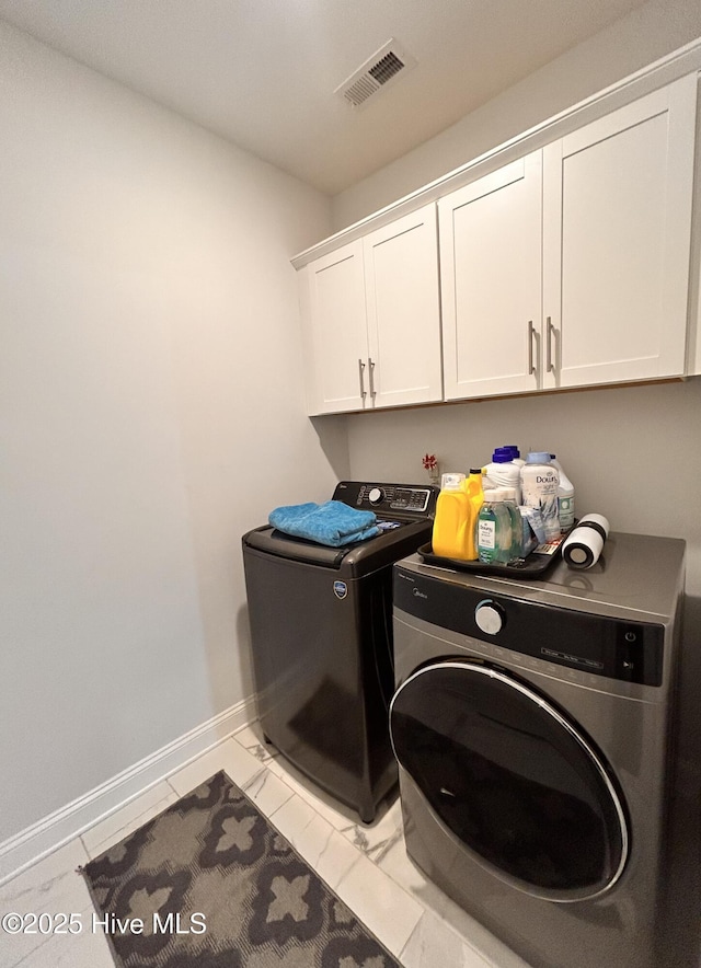 clothes washing area with marble finish floor, washer and clothes dryer, cabinet space, visible vents, and baseboards