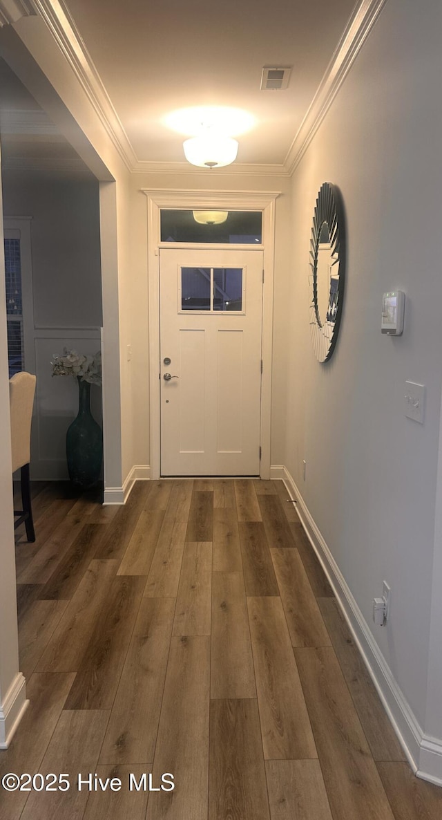 corridor featuring dark wood-style flooring, visible vents, crown molding, and baseboards