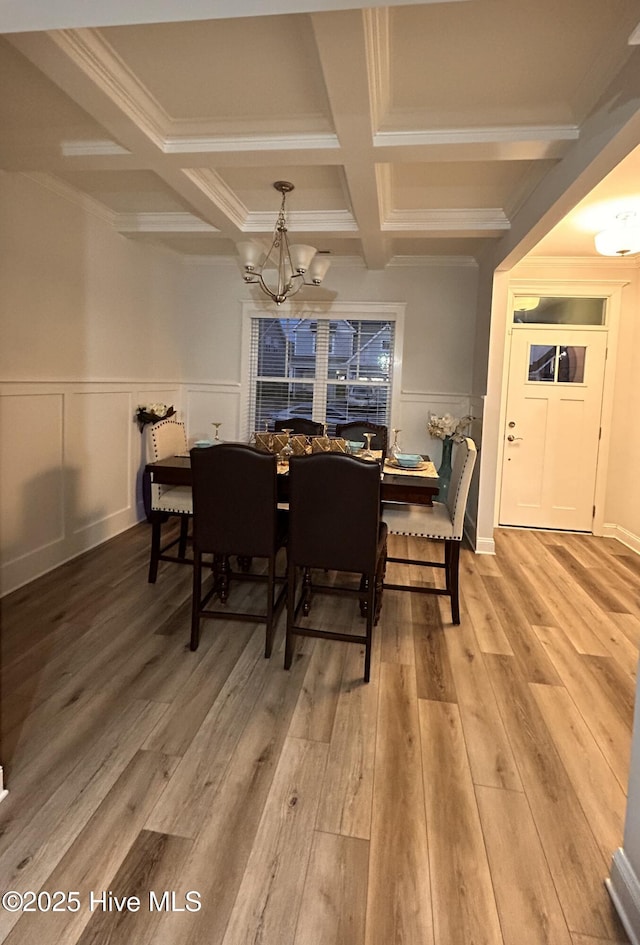 dining room with coffered ceiling, a wainscoted wall, light wood-style flooring, beamed ceiling, and a notable chandelier