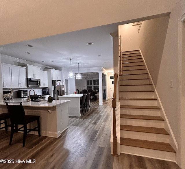 kitchen with appliances with stainless steel finishes, a kitchen breakfast bar, wood finished floors, a center island, and light countertops