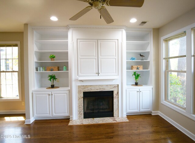 155 Abbington Pl SW, Ocean Isle Beach, NC 28469 - unfurnished living room featuring baseboards, dark wood-style flooring, ceiling fan, a premium fireplace, and built in shelves