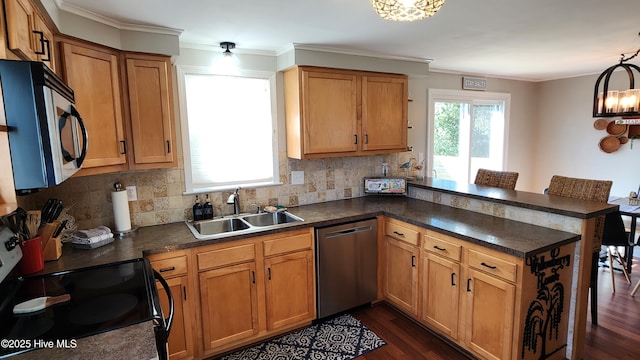 kitchen with dark countertops, stainless steel appliances, a peninsula, and a sink