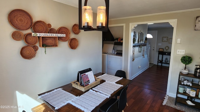 dining room with a notable chandelier, dark wood-type flooring, washing machine and dryer, and crown molding