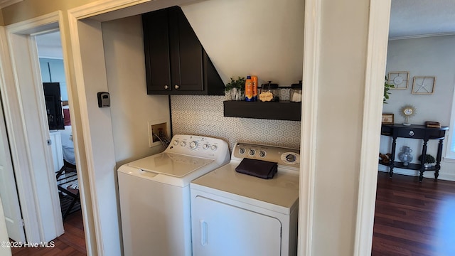 washroom with dark wood-style flooring, washer and clothes dryer, and cabinet space