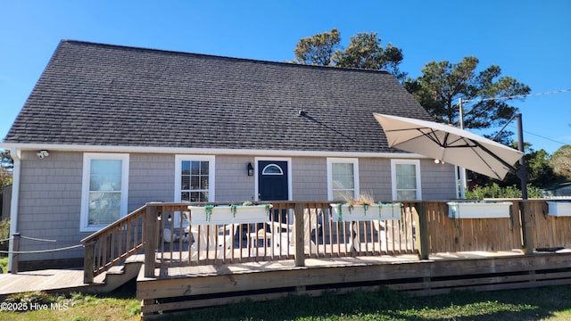 rear view of property featuring a shingled roof and a wooden deck