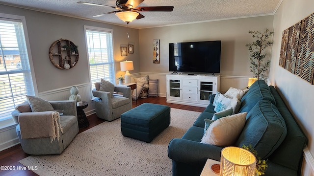 living room featuring a wainscoted wall, ornamental molding, a textured ceiling, and wood finished floors