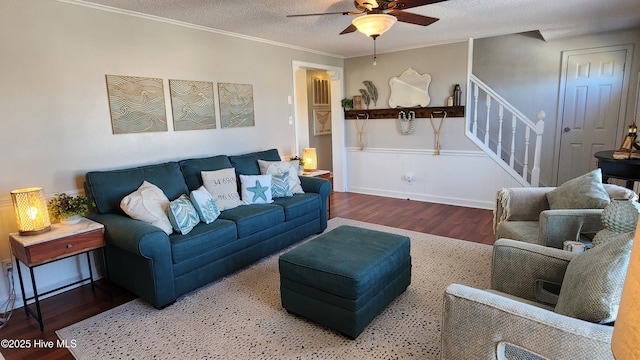 living room featuring ornamental molding, ceiling fan, a textured ceiling, wood finished floors, and stairs