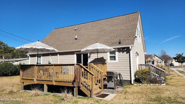 back of house featuring a shingled roof, stairs, a deck, and a lawn