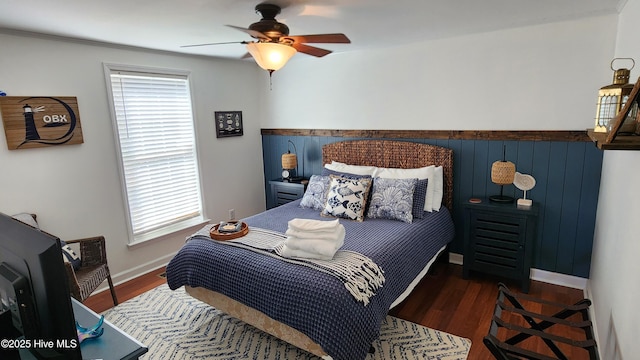 bedroom with ceiling fan, dark wood-style flooring, and baseboards