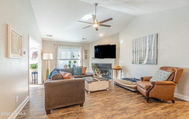 living room with visible vents, a ceiling fan, wood finished floors, vaulted ceiling, and a fireplace