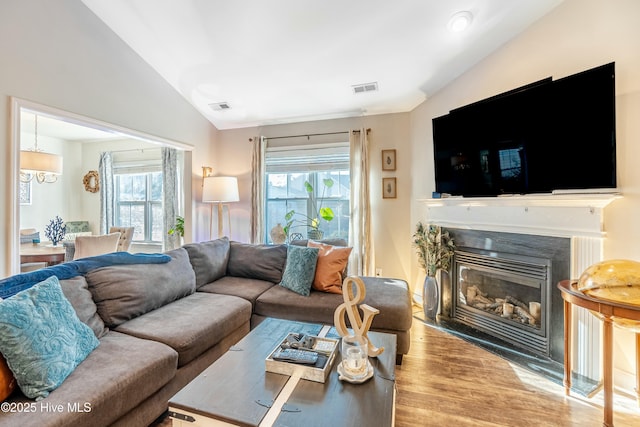 living area with vaulted ceiling, wood finished floors, visible vents, and a healthy amount of sunlight