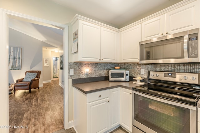 kitchen featuring dark countertops, white cabinetry, appliances with stainless steel finishes, and backsplash