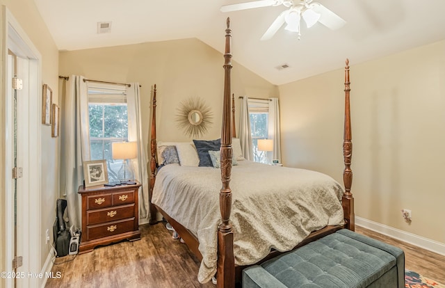 bedroom with baseboards, visible vents, vaulted ceiling, and wood finished floors