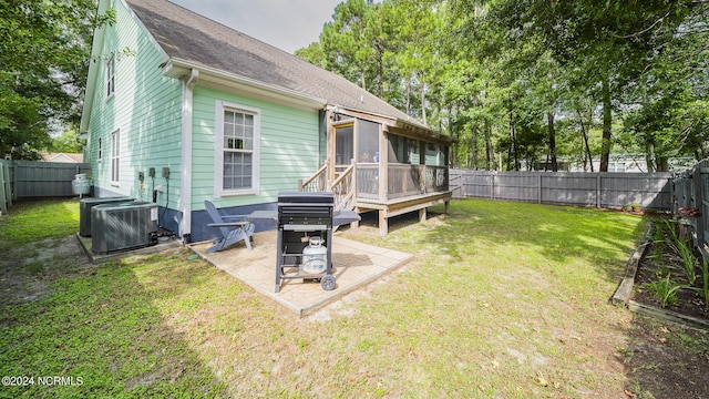 rear view of property featuring central AC, a patio, a fenced backyard, and a sunroom