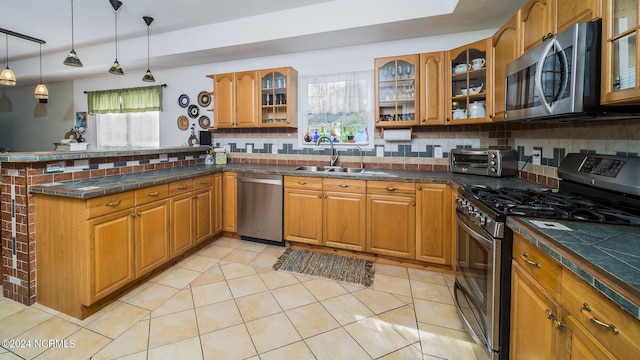 kitchen featuring stainless steel appliances, brown cabinetry, a sink, and glass insert cabinets