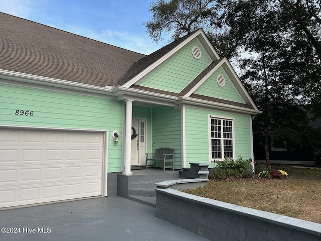 view of front of house featuring an attached garage, driveway, and roof with shingles