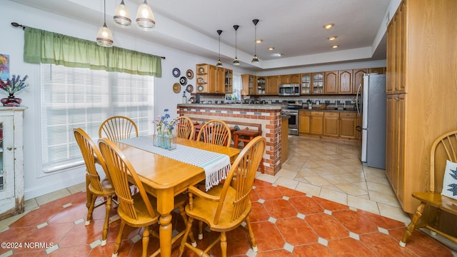 dining area with a tray ceiling and light tile patterned floors