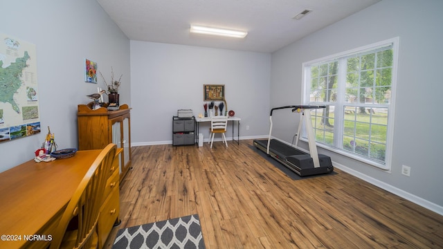 workout area with wood finished floors, visible vents, and baseboards