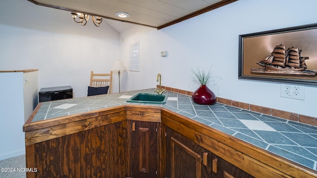 kitchen featuring tile counters, vaulted ceiling, a sink, and a peninsula