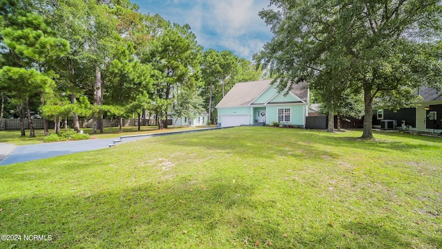 view of yard with central AC unit, an attached garage, and fence