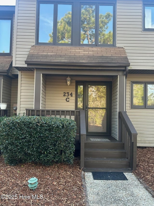 entrance to property featuring roof with shingles