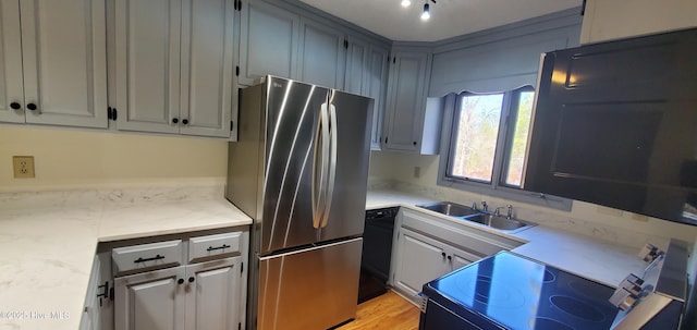 kitchen featuring electric range, a sink, black dishwasher, freestanding refrigerator, and light stone countertops