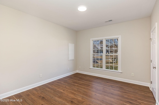 unfurnished room featuring dark wood-style flooring, visible vents, and baseboards