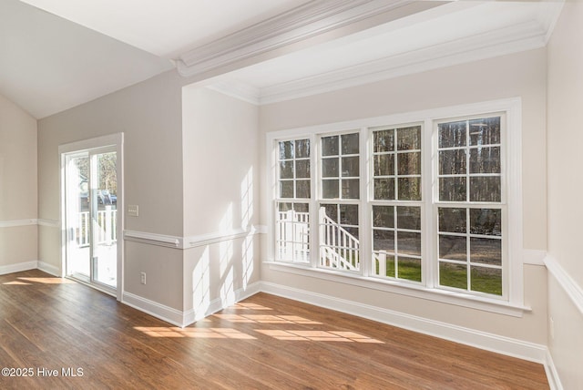 spare room with dark wood-style floors, baseboards, vaulted ceiling, and ornamental molding