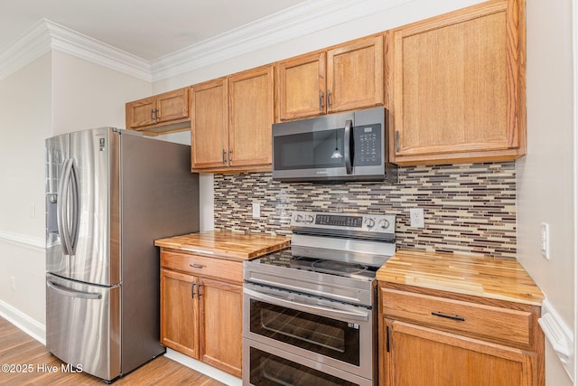 kitchen featuring light wood-style flooring, butcher block countertops, appliances with stainless steel finishes, ornamental molding, and backsplash