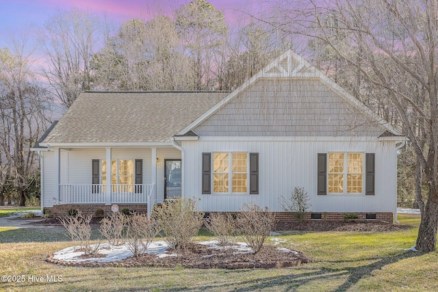 view of front of property with covered porch, a yard, a shingled roof, and crawl space