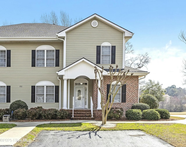 traditional-style home featuring brick siding and a shingled roof