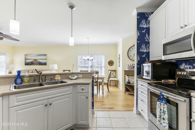 kitchen with stainless steel appliances, a sink, white cabinets, and crown molding