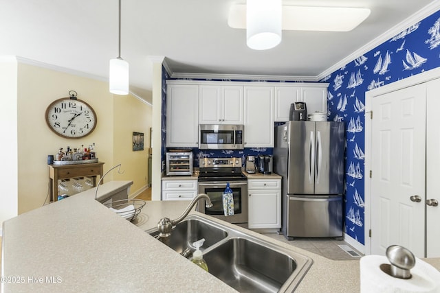 kitchen with appliances with stainless steel finishes, ornamental molding, white cabinetry, pendant lighting, and a sink