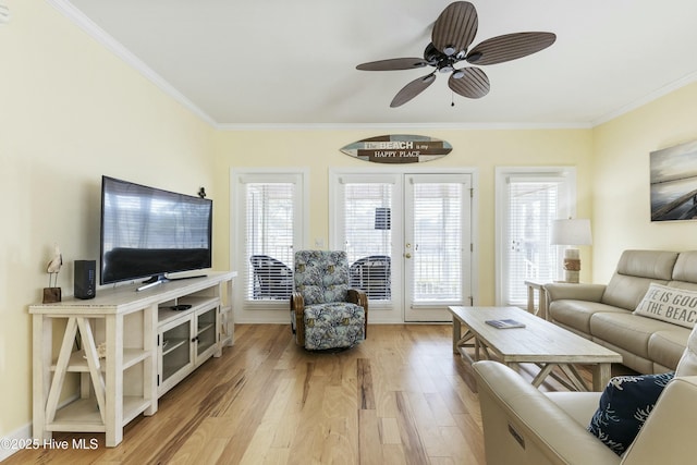 living room featuring light wood-style floors, a wealth of natural light, crown molding, and a ceiling fan