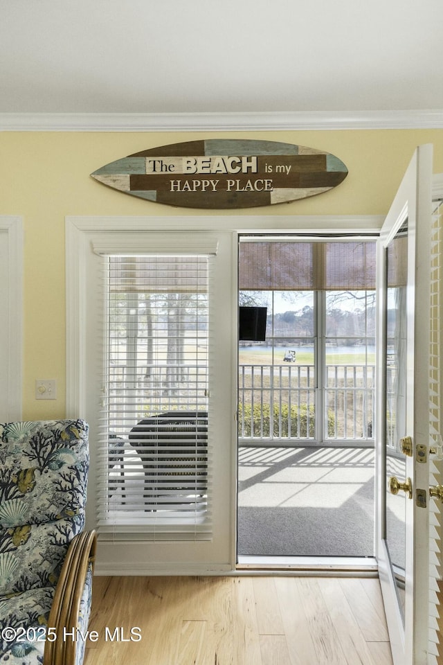 entryway with ornamental molding and wood finished floors