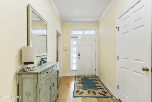 entryway with light wood-style floors, baseboards, and crown molding