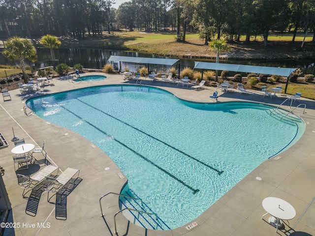 pool with a patio, fence, and a hot tub