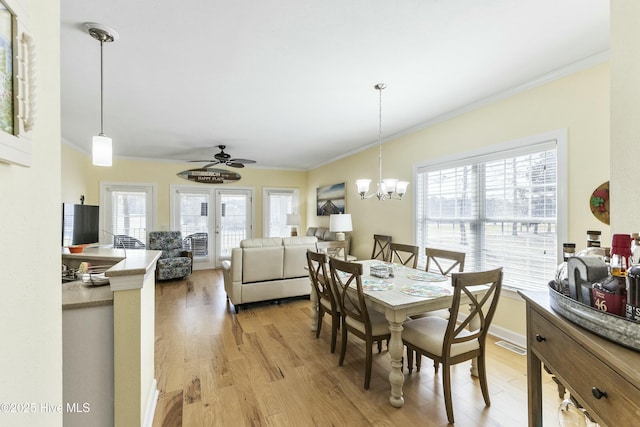 dining room with ornamental molding, a wealth of natural light, and light wood-style flooring