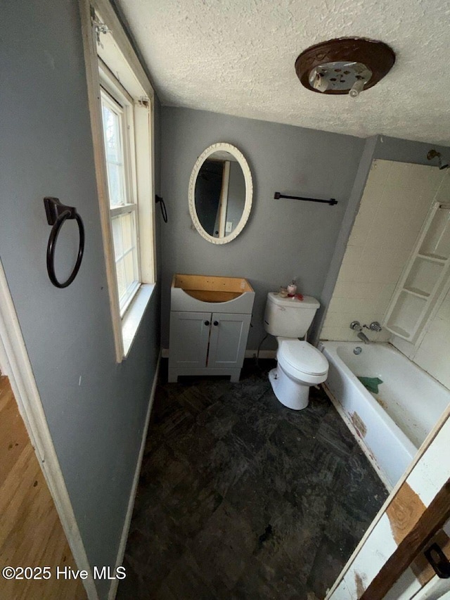 full bath featuring baseboards, bathing tub / shower combination, toilet, a textured ceiling, and vanity