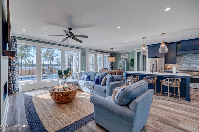 living room with recessed lighting, baseboards, ornamental molding, and a glass covered fireplace