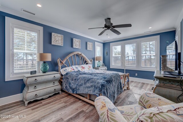 bedroom with ceiling fan, wood finished floors, visible vents, and crown molding