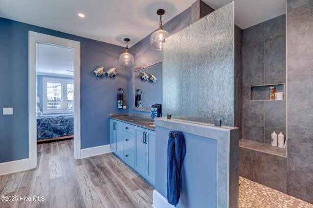 bathroom featuring baseboards, wood finished floors, a tile shower, a freestanding bath, and recessed lighting