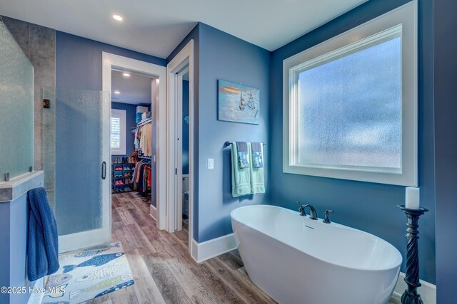 full bathroom featuring a freestanding tub, wood finished floors, and baseboards