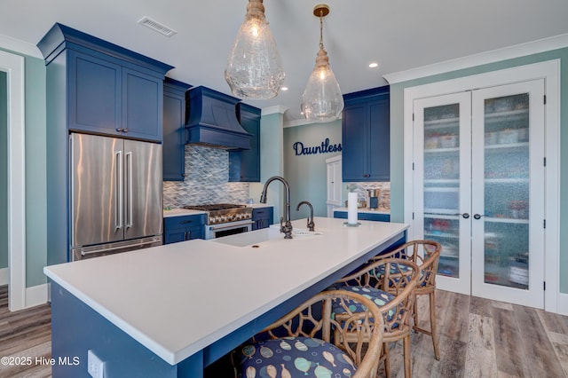 kitchen featuring blue cabinets, tasteful backsplash, visible vents, and high end appliances